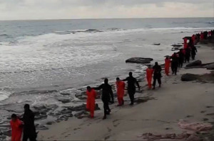 This image made from a video released Sunday Feb. 15, 2015 by militants in Libya claiming loyalty to the Islamic State group purportedly shows Egyptian Coptic Christians in orange jumpsuits being led along a beach, each accompanied by a masked militant. Later in the video, the men are made to kneel and one militant addresses the camera in English before the men are simultaneously beheaded. The Associated Press could not immediately independently verify the video. (AP Photo)