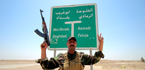 A member of the allied Iraqi forces consisting of the Iraqi army and fighters from the Popular Mobilisation units, poses for a photo in front of a road sign during clashes with Islamic State (IS) group fighters on the outskirts of Fallujah, in Iraq's Anbar province, on August 13, 2015. Anbar, Iraq's largest province, has been rocked by violence since the beginning of 2014, months before the IS jihadist group launched a massive nationwide offensive that saw it conquer swathes of the country. AFP PHOTO / HAIDAR MOHAMMED ALI        (Photo credit should read HAIDAR MOHAMMED ALI/AFP/Getty Images)