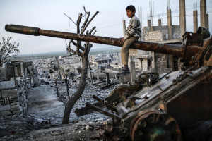 A Syrian Kurdish boy sits on a destroyed tank in the Syrian town of Kobane, also known as Ain al-Arab, on March 27, 2015. Islamic State (IS) fighters were driven out of Kobane on January 26 by Kurdish and allied forces. AFP PHOTO/YASIN AKGUL (Photo credit should read YASIN AKGUL/AFP/Getty Images)