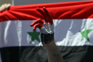A Syrian protester makes a victory sign near their national flag during a protest calling for Syria's President Bashar al-Assad to step down, in front of the Syrian embassy in Amman April 24, 2011. At least 100 people were killed in Syria on Friday, the highest toll in five weeks of unrest, when security forces shot protesters demanding political freedoms and an end to corruption in their country, ruled for 41 years by the Assad dynasty. REUTERS/Muhammad Hamed (JORDAN - Tags: POLITICS CIVIL UNREST)
